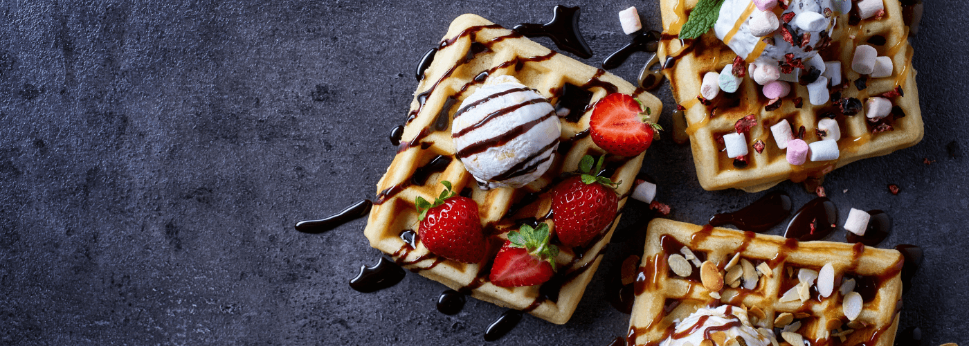 Waffles served with different toppings on black tray