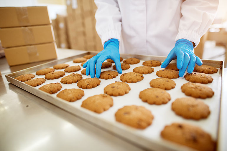 person handling cookies from tray with gloves on