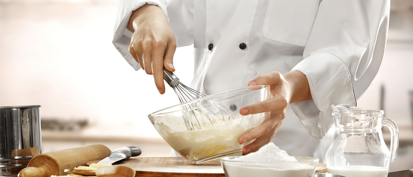 Chef whisking batter in a clear bowl