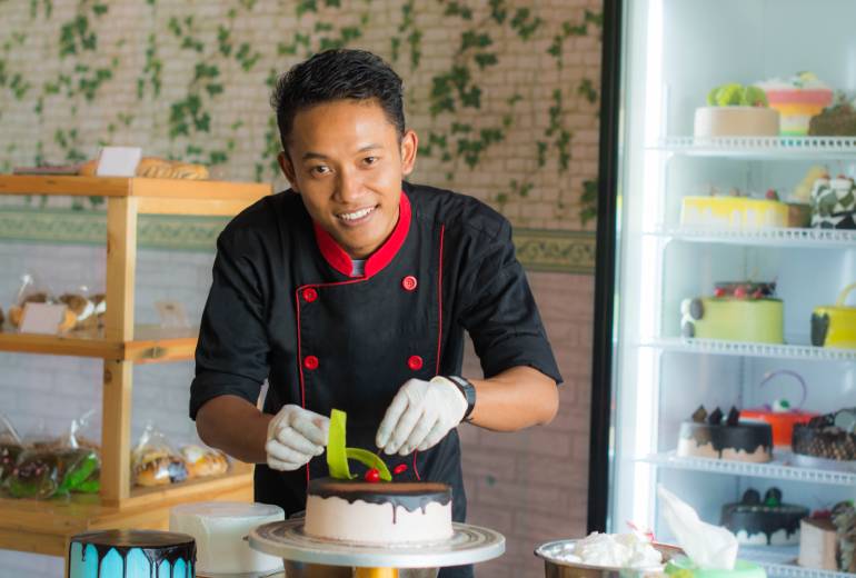 Chef smiling while garnishing cake